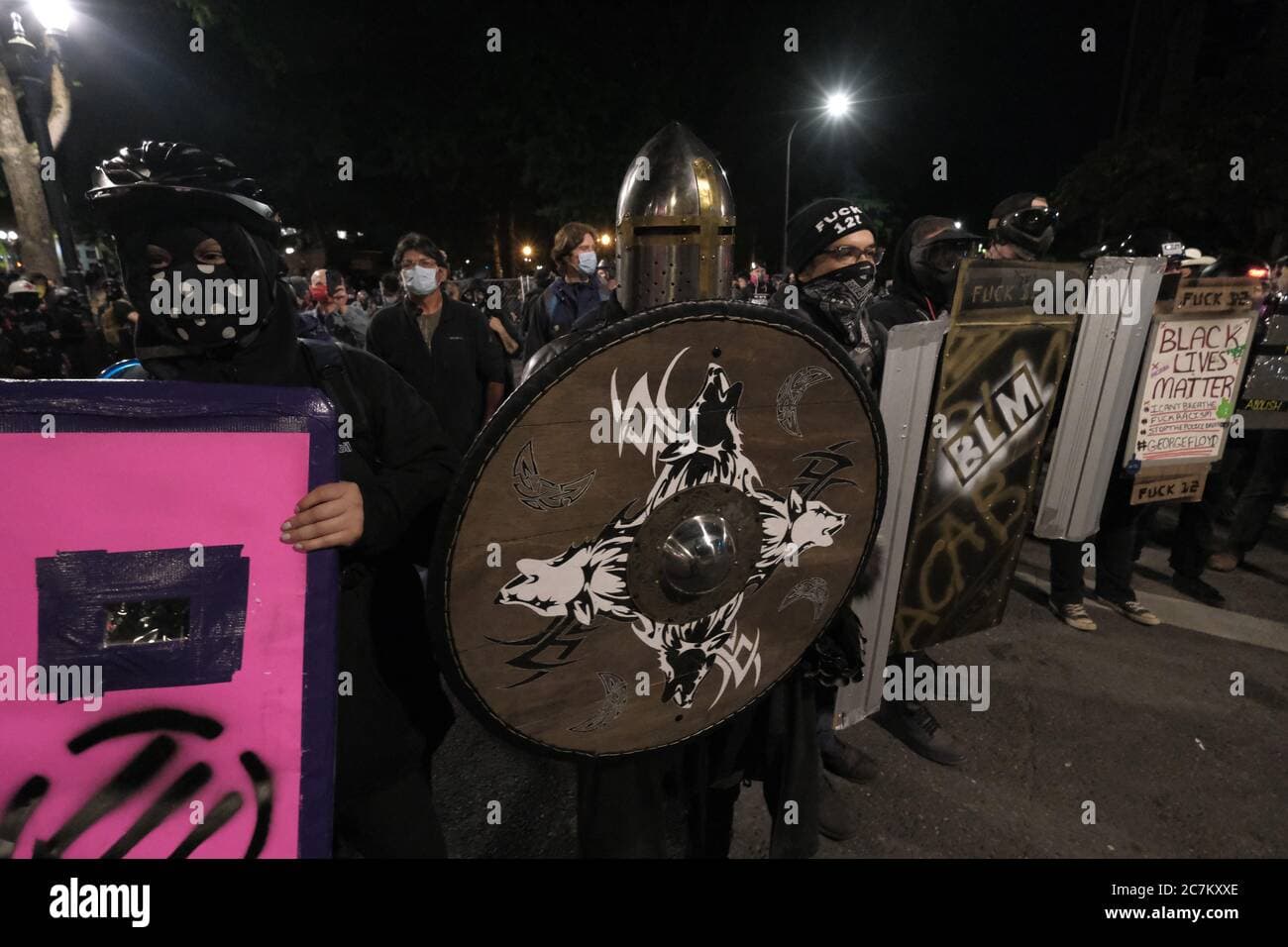 Protesters holding shields line up opposite federal building